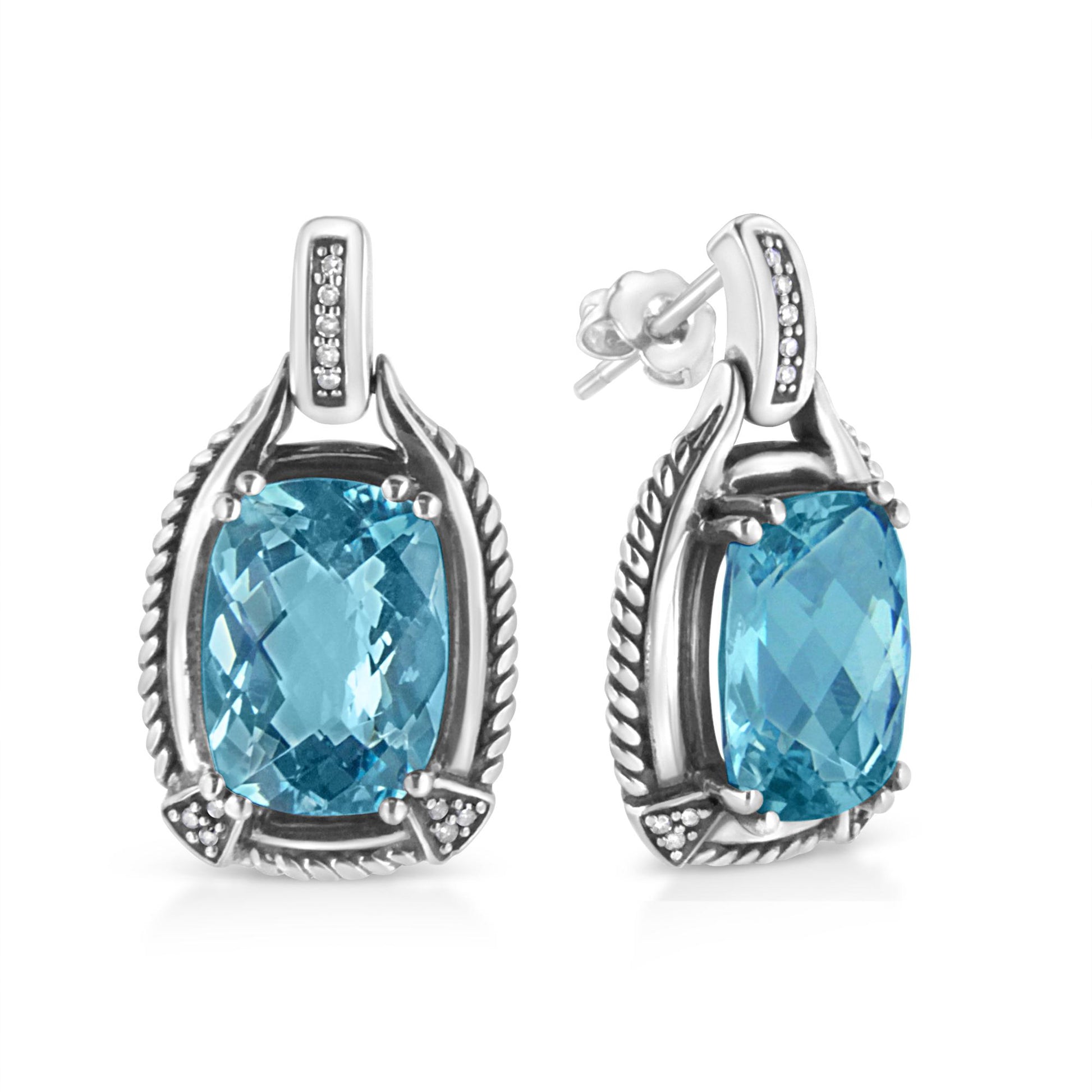 Front and side angled view of white metal earrings with cushion-shaped blue gemstones prong-set in the center, surrounded by white round gemstones in an invisible setting.