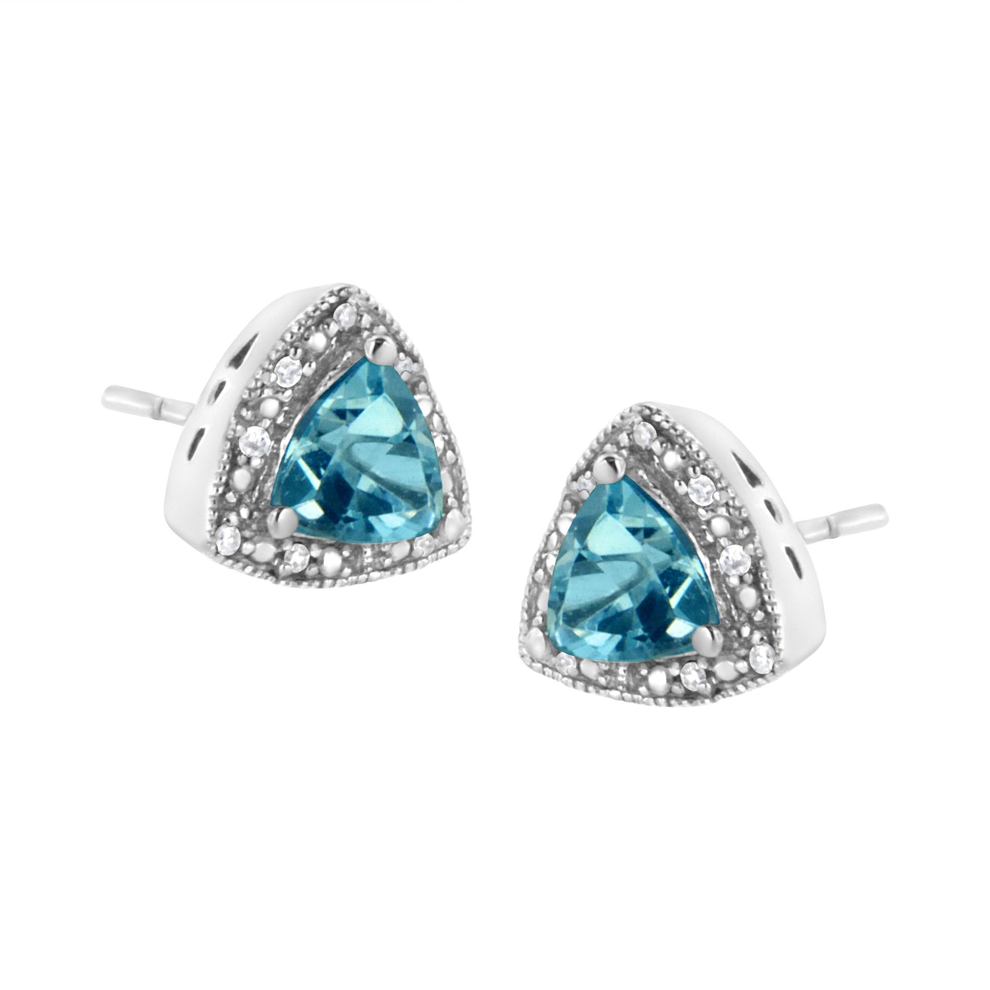 Close-up front angle of white metal stud earrings with triangular blue gemstones surrounded by small round white gemstones in prong settings.