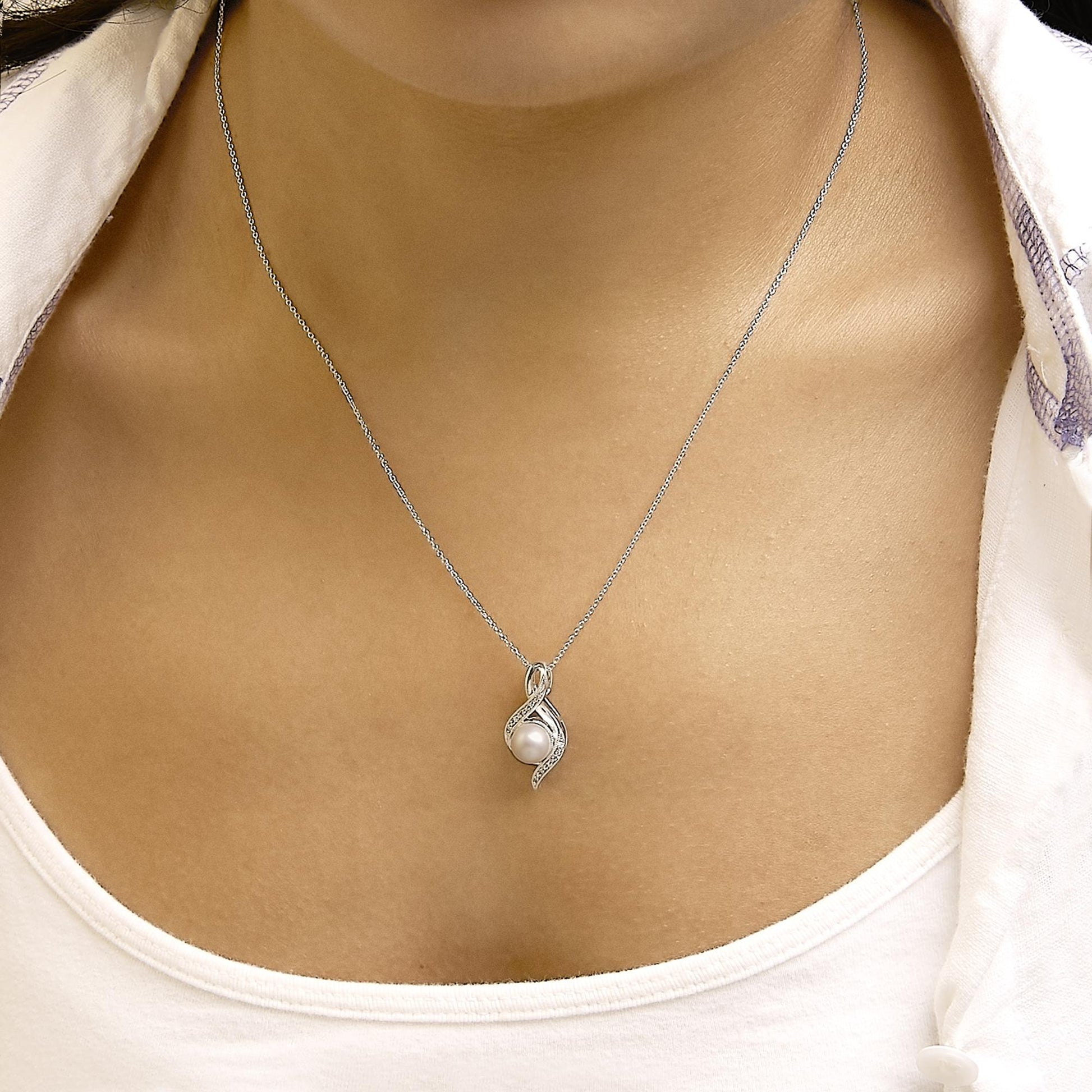 Close-up of a white metal necklace with a pendant featuring a round white gemstone encased in a twisted design accented with small white gemstones, shown worn on a model.