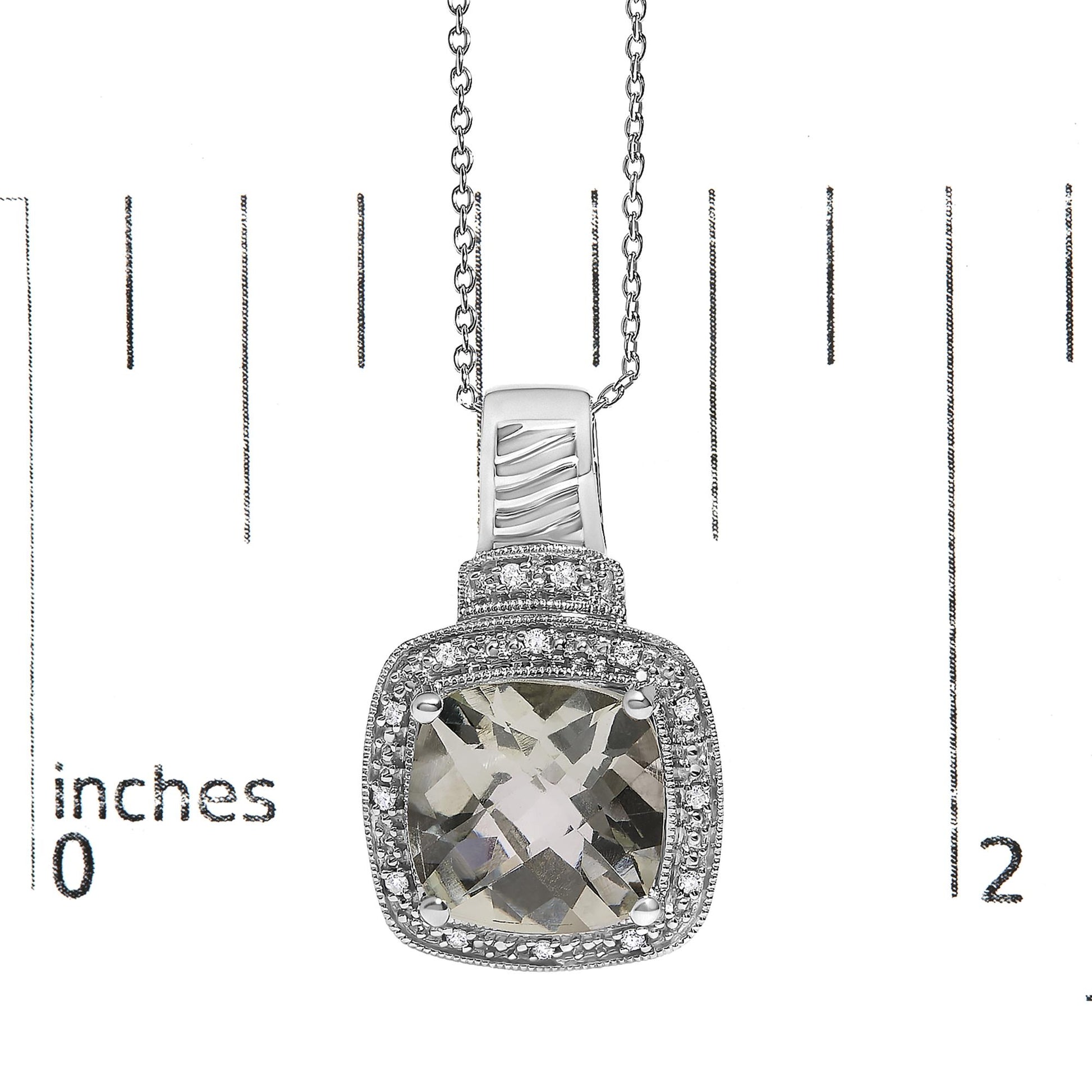 Close-up front view of a white metal necklace with a cushion-shaped green gemstone pendant surrounded by small round white gemstones in pave settings, shown on a scale.