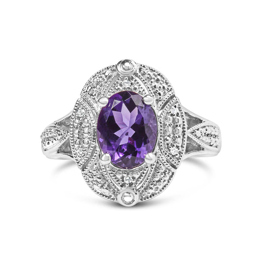 Front-facing shot of a white metal ring featuring an oval purple gemstone in the center with surrounding round white gemstones in prong settings.