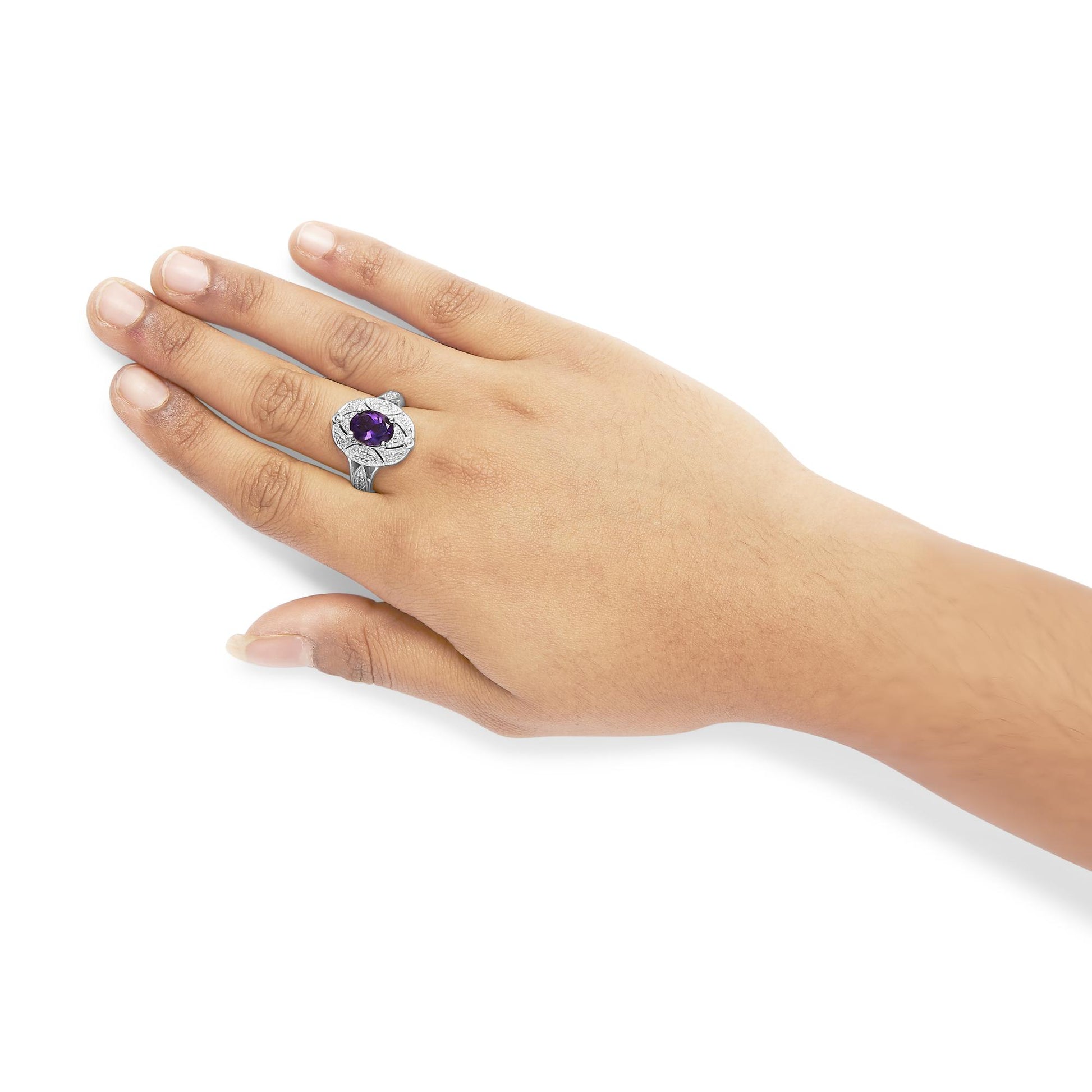 White metal ring with a purple oval gemstone surrounded by white round gemstones, worn on a model’s hand, top view angle.