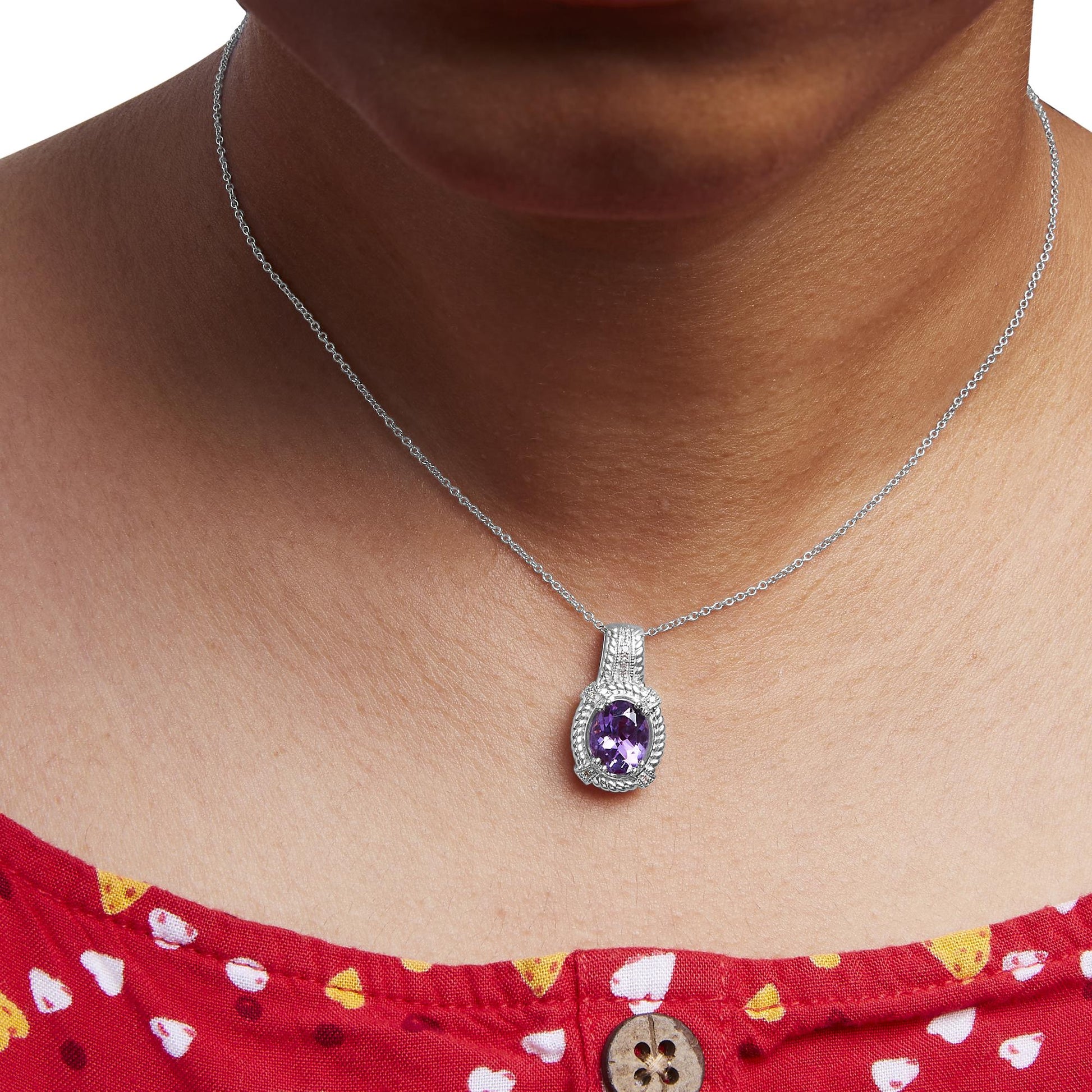Close-up front view of a white necklace on a model featuring an oval purple gemstone pendant surrounded by round white gemstones in a pave setting.