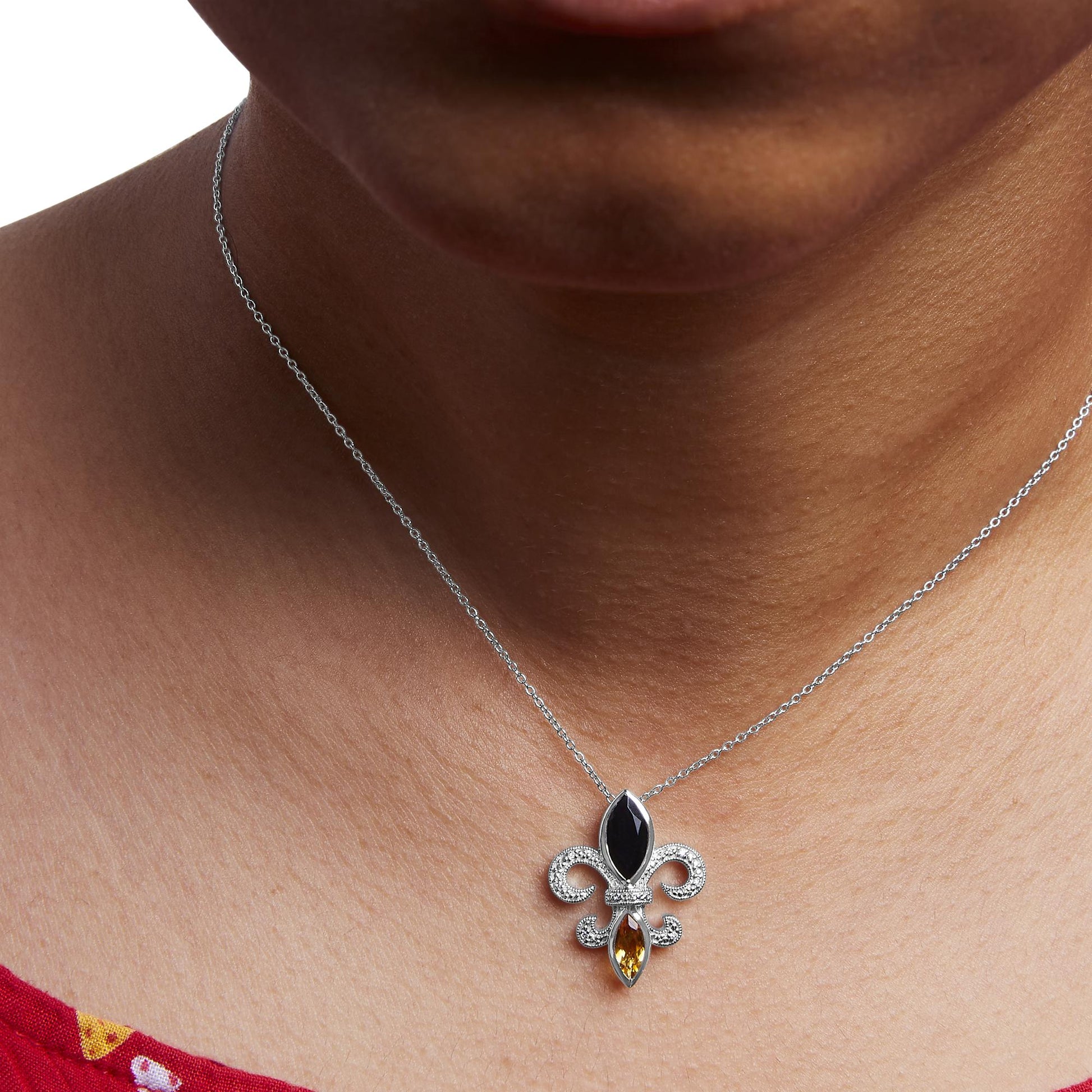 Close-up front view of a white metal necklace on a model's neck, featuring a pendant with a black marquise-shaped gemstone, a yellow marquise-shaped gemstone, and intricate details with small round white gemstones in prong settings.