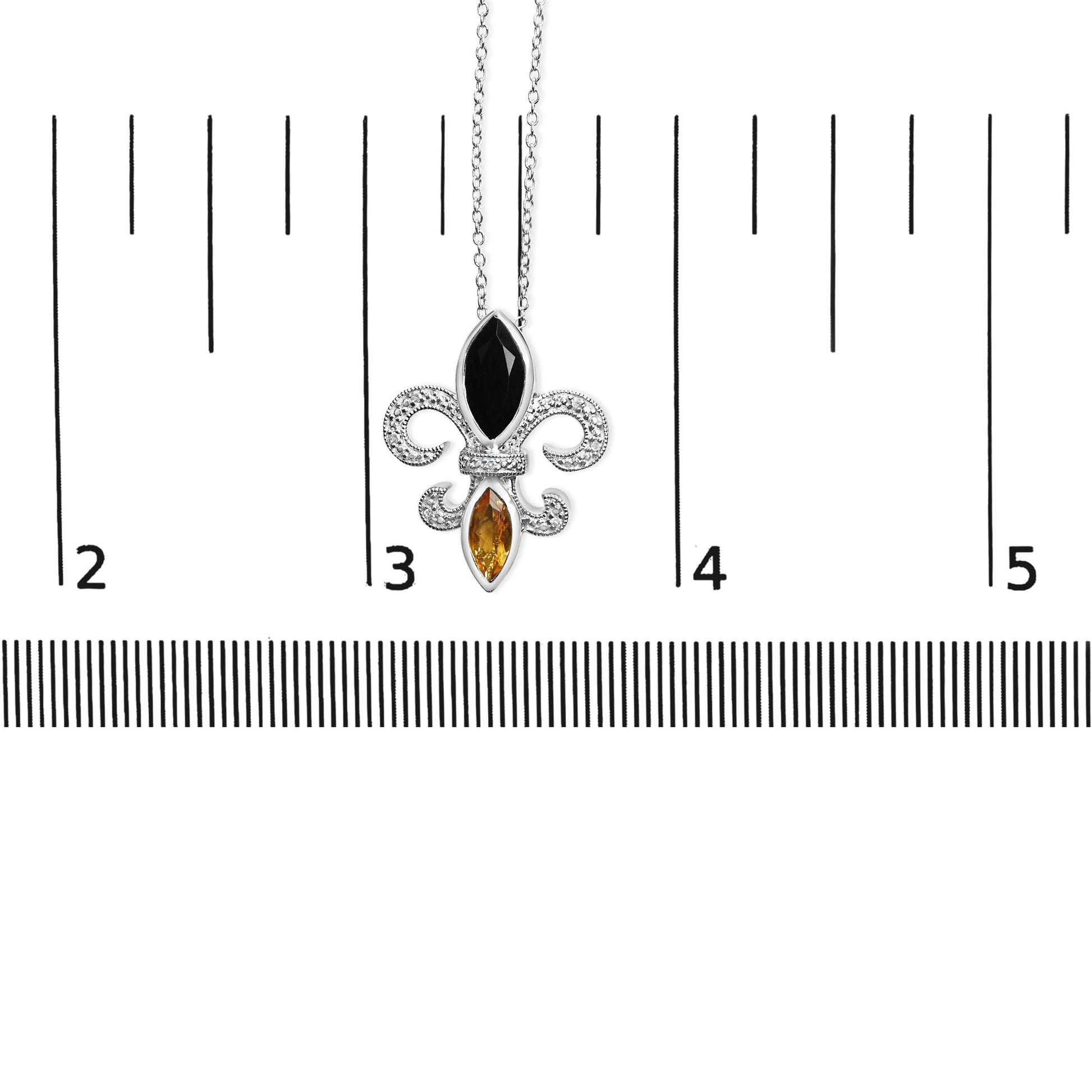 Close-up front view of a white metal necklace pendant with a black marquise-shaped bezel-set gemstone on top, a yellow marquise-shaped bezel-set gemstone below, and surrounded by seven round prong-set white gemstones, displayed on a ruler for size reference.