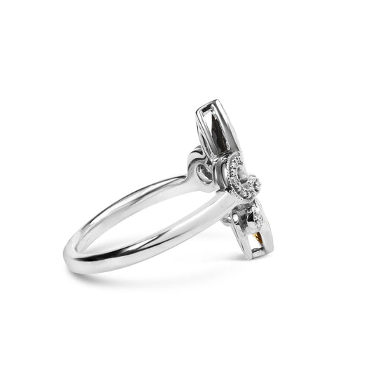 White metal ring shown from side angle, featuring a cross design with small round white gemstones in pave setting and orange marquise-shaped gemstones in bezel and prong settings.