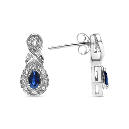 Front and side views of white metal earrings with an infinity loop design, featuring a pear-shaped blue gemstone surrounded by small round white gemstones, with a post and butterfly back visible on the side view.
