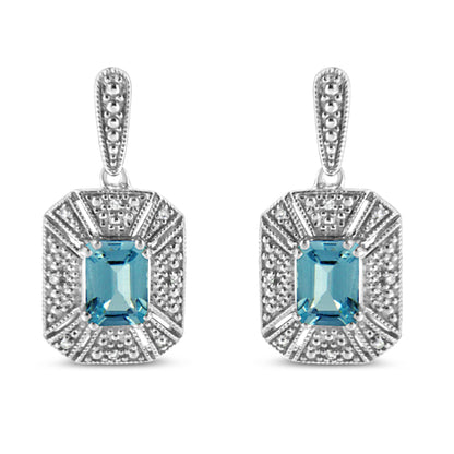 Front view of white metal earrings with rectangular blue gemstones in prong settings surrounded by pave-set round white gemstones.