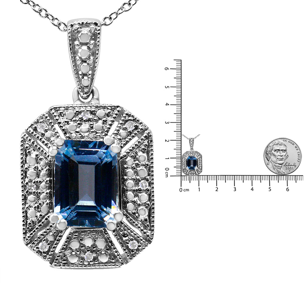 Close-up front view of a white metal necklace pendant with a large blue emerald-shaped gemstone in the center, surrounded by white round gemstones in a geometric pattern, shown next to a ruler and coin for size reference.