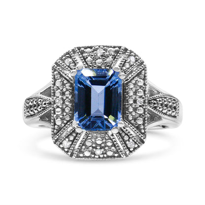 Front angle white metal ring with a large blue emerald-shaped gemstone in the center, surrounded by smaller round white gemstones in a detailed setting.