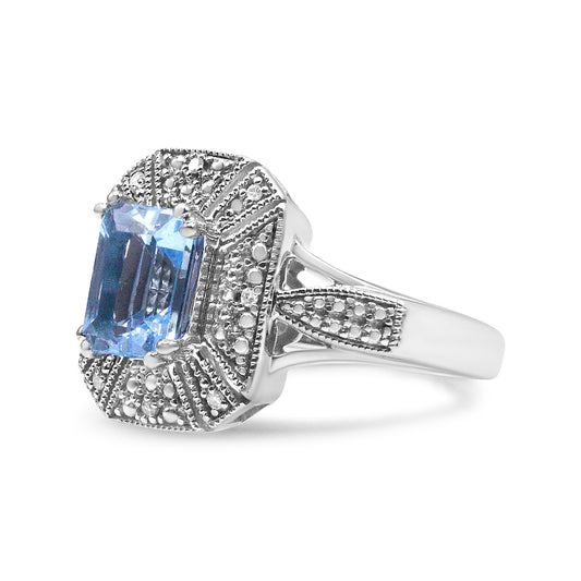 Side angle view of a white ring featuring one blue emerald-shaped gemstone in a prong setting surrounded by small round white gemstones in prong settings on the band and around the centerpiece.