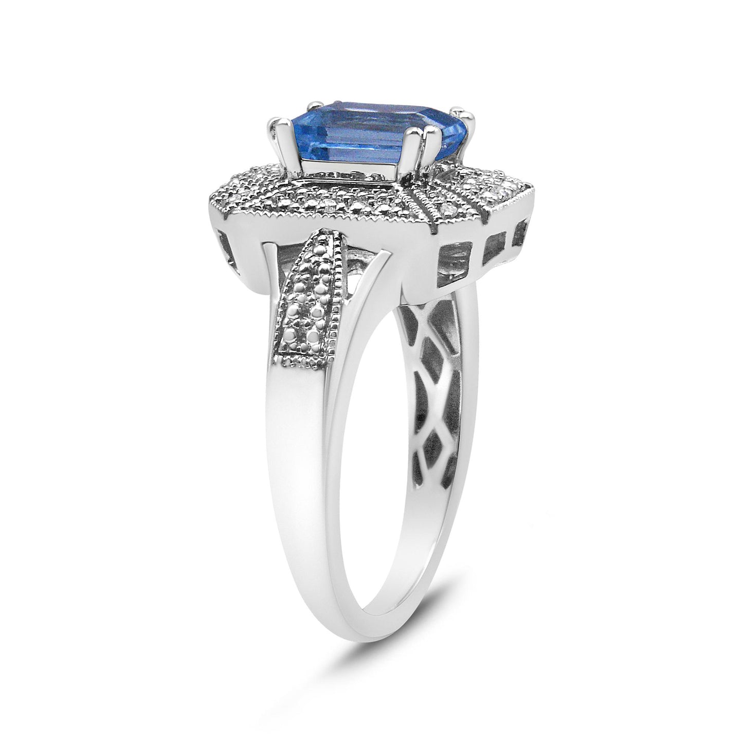 White metal ring with a blue emerald-shaped gemstone and multiple round white gemstones in prong settings, shown from a side angle.