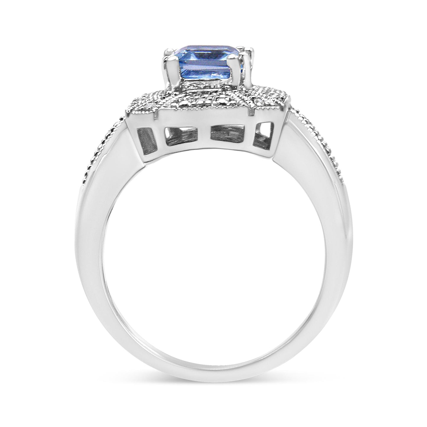 White metal ring shown from the side angle featuring a blue gemstone in an emerald shape flanked by small round white gemstones in prong settings.