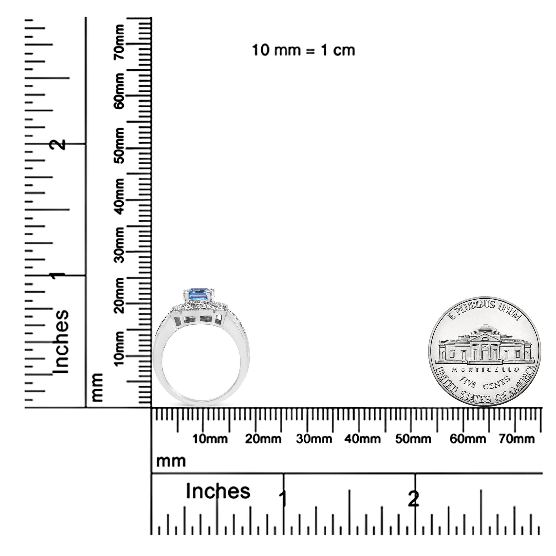 White metal ring with a prong-set blue emerald-shaped gemstone center, surrounded by prong-set round white gemstones, shown from the side on a ruler and scale for size reference.