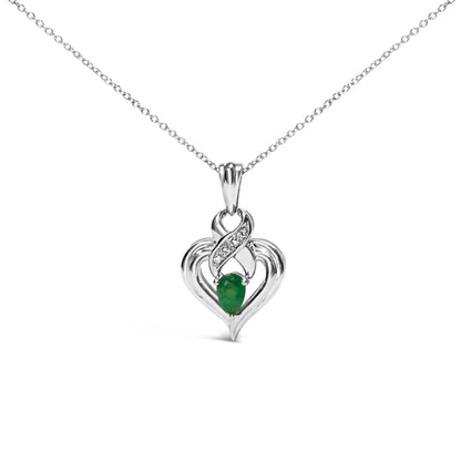 Front view of a white metal heart-shaped necklace pendant with a pear-shaped green gemstone at the center and a curved section above set with four small round white gemstones, hanging on a delicate white metal chain.