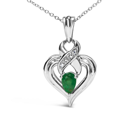 Close-up front view of a white metal heart-shaped necklace pendant with a pear-shaped green gemstone centered at the bottom and a swirl of white gemstones above it.