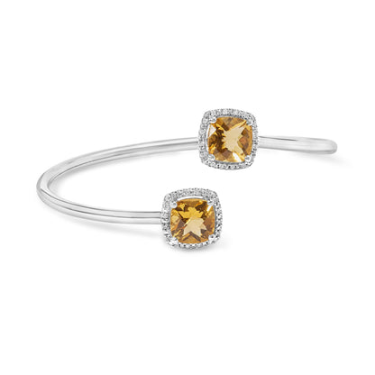White metal open cuff bracelet with two cushion-shaped yellow gemstones surrounded by small round white gemstones, shown in a close-up angled front view.