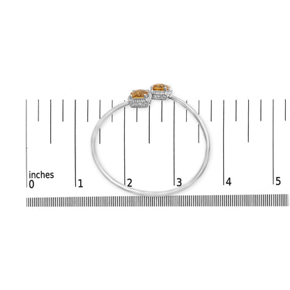 Top-down view of a white metal bracelet with two yellow cushion-shaped gemstones and multiple small round white gemstones. The bracelet is placed on a ruler for size reference.