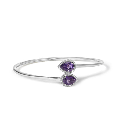 White metal open-ended bracelet with two pear-shaped purple gemstones surrounded by small round white gemstones, shown in a front angled view.