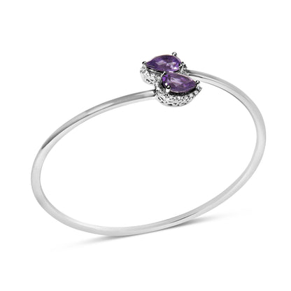 White metal open bangle bracelet with two pear-shaped purple gemstones surrounded by small round white gemstones, shown at a slight angle on a white background.
