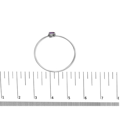 Top view of a white metal bracelet with a purple pear-shaped gemstone and round white gemstones surrounding it, placed on a ruler for size reference.