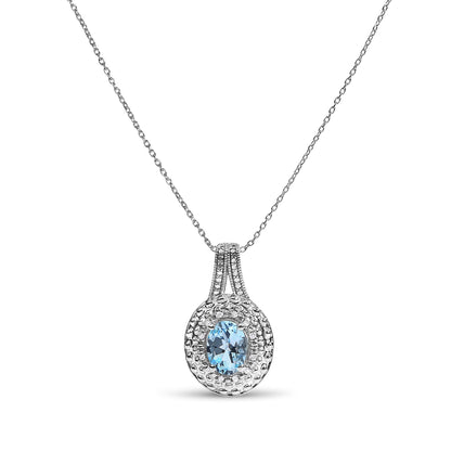 Close-up front angle of a white metal necklace with a pendant featuring an oval blue gemstone surrounded by round white gemstones in pave setting.