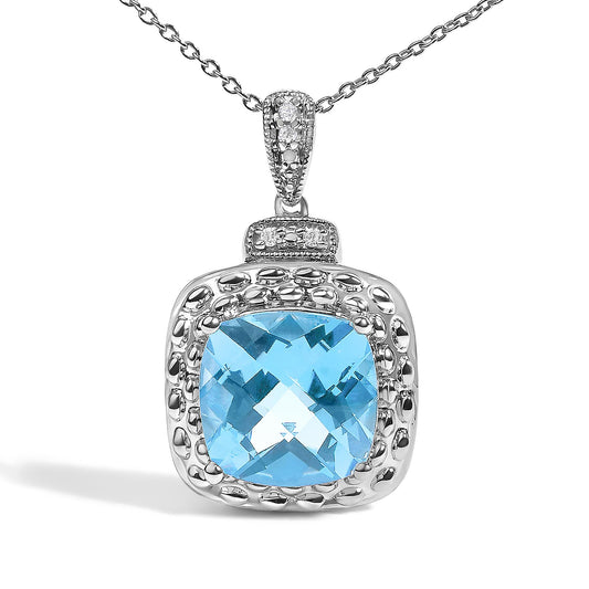 Close-up front view of a white metal necklace pendant featuring a large blue cushion-shaped gemstone surrounded by textured metal details and small white round gemstones in a pave setting, shown on a white background.