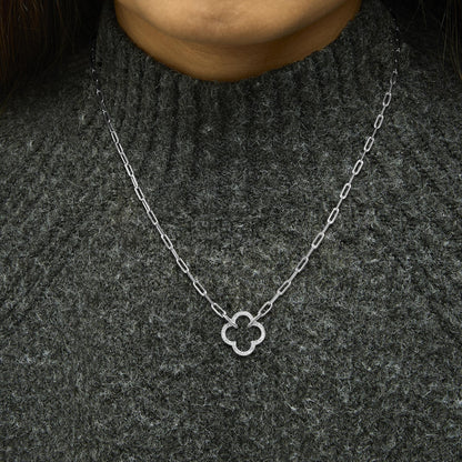 White metal necklace with a clover-shaped pendant set with white gemstones in a pave setting, shown worn on a model from the front angle.