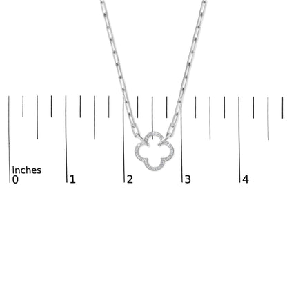 Close-up front view of a white metal necklace with a pendant shaped like a four-leaf clover outlined with pave-set white gemstones, shown on a scale.