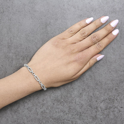 Close-up angled shot of a model's wrist wearing a white metal bracelet with chain links, some links adorned with white gemstones in a pave setting.