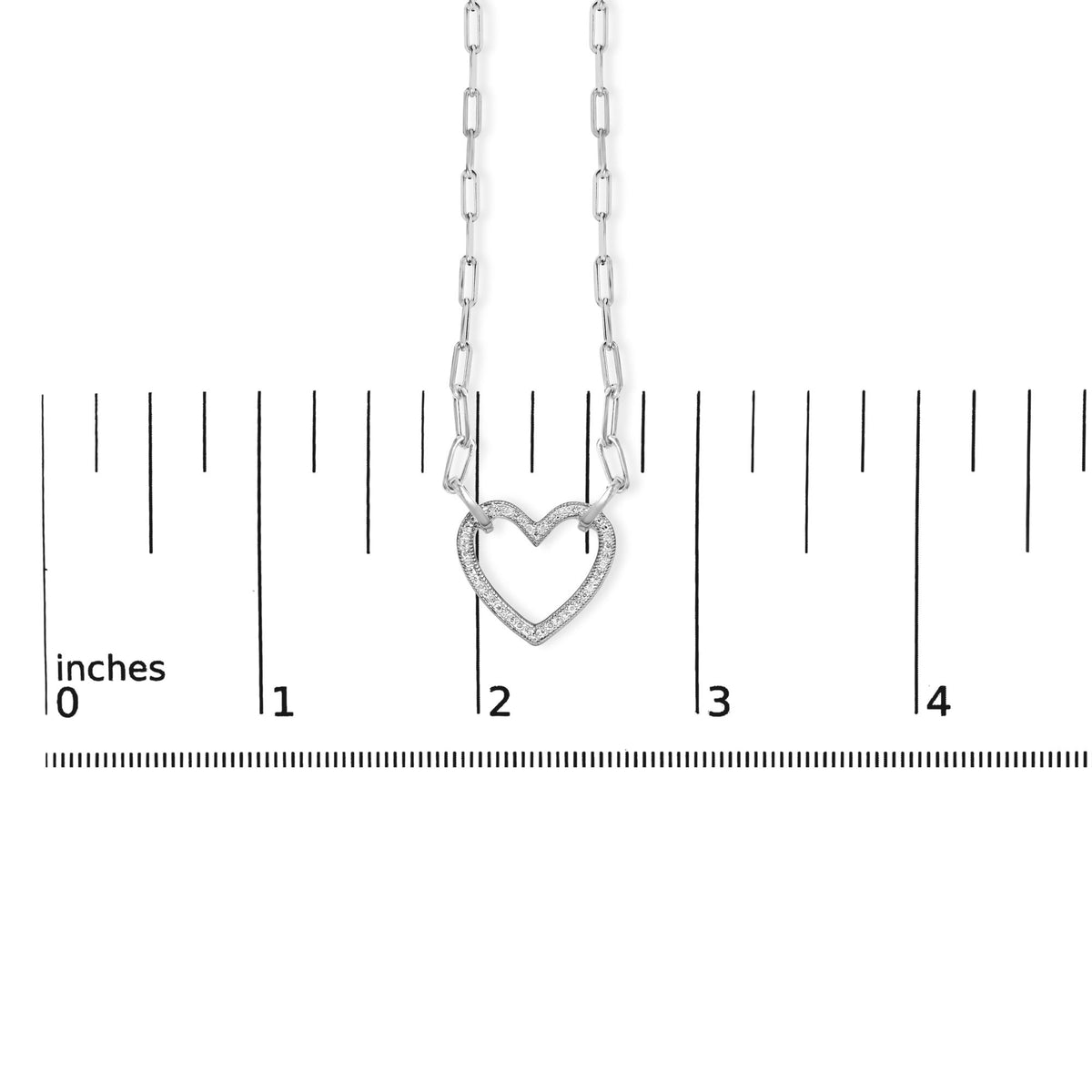 Close-up front view of white metal necklace with heart-shaped pendant pavé set with white gemstones, shown on a scale.