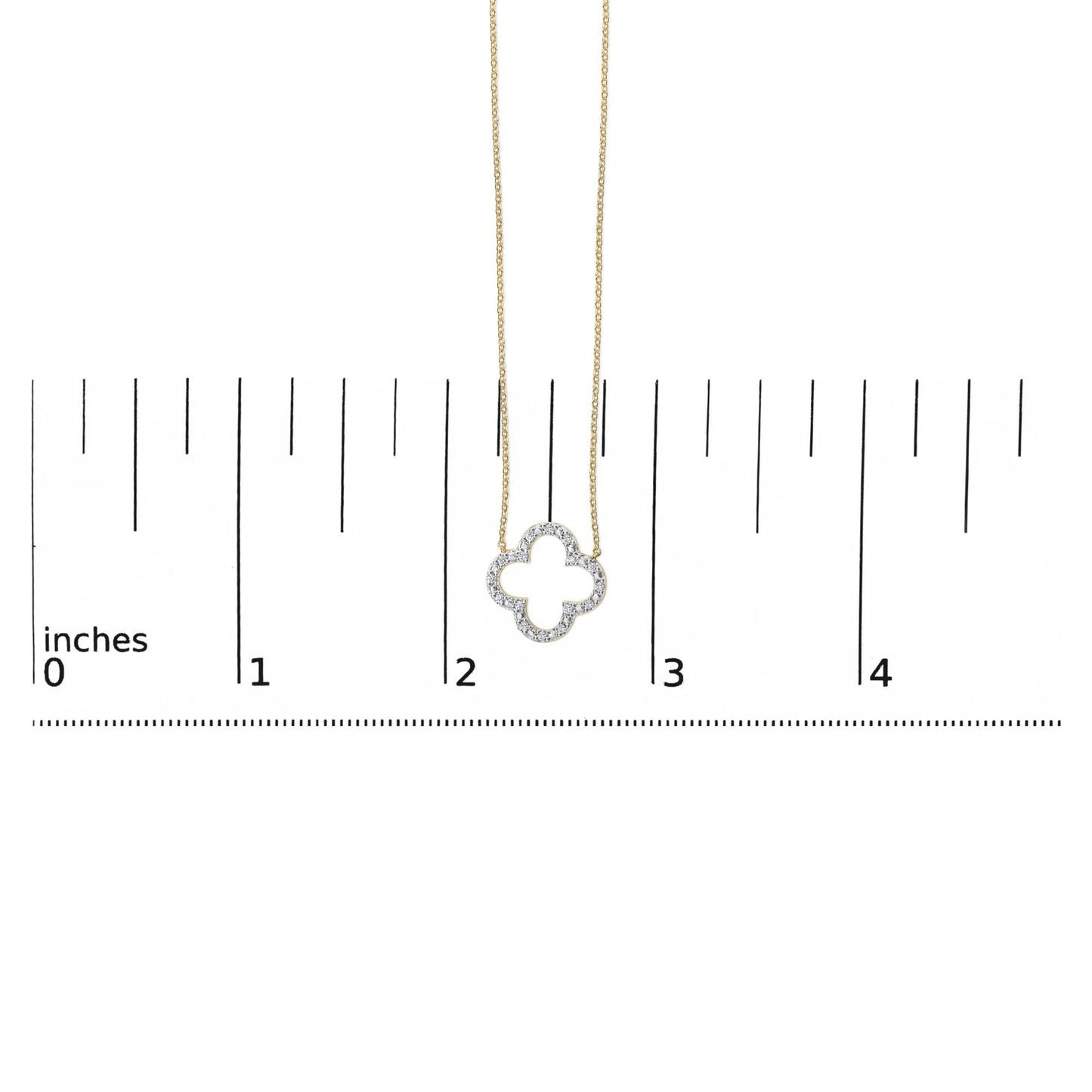 Yellow metal necklace with a clover-shaped pendant featuring round white gemstones in prong setting, shown on a scale from a front angle.