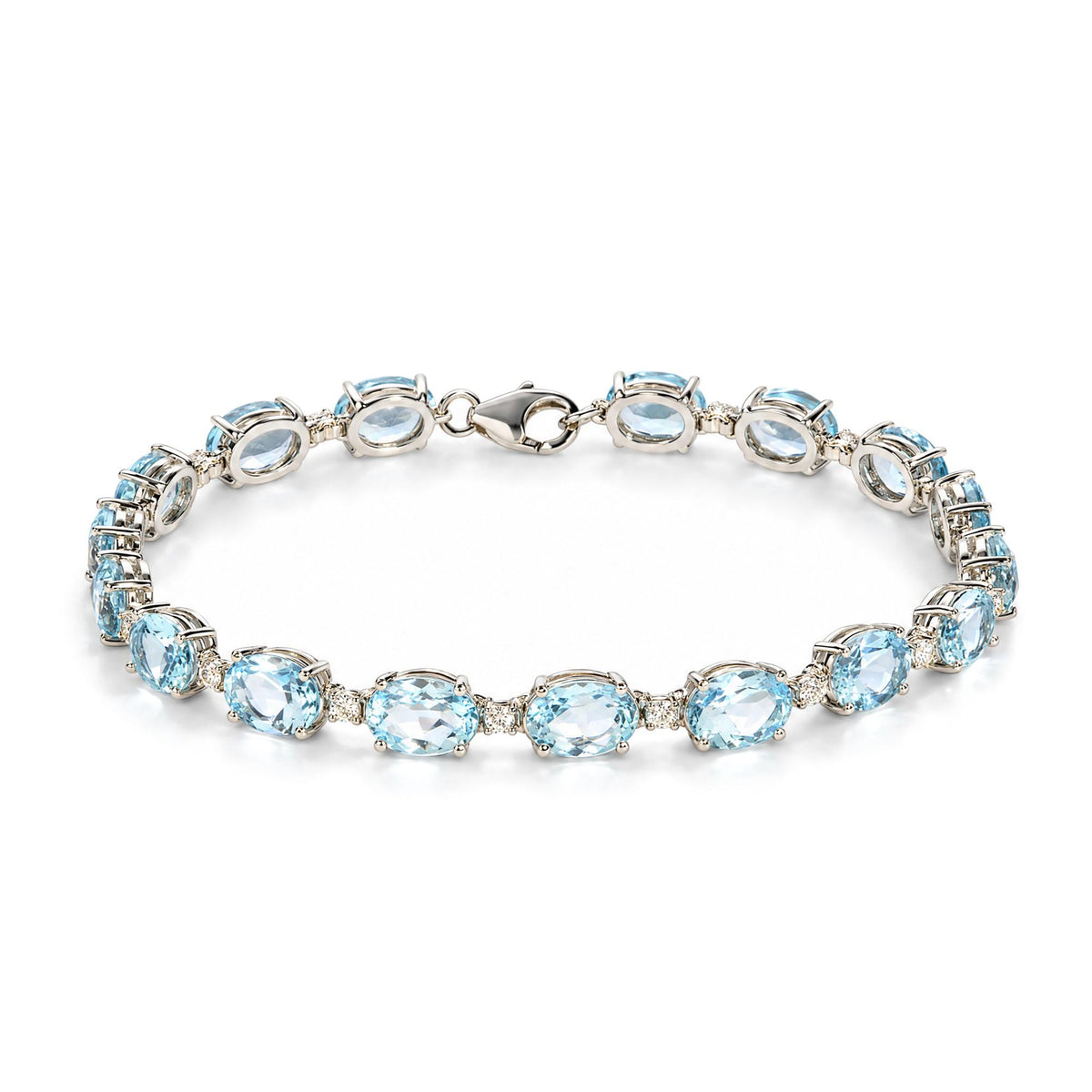 Close-up angled top view of a white metal bracelet featuring oval blue gemstones and small round white gemstones in prong settings, shown on a white background.
