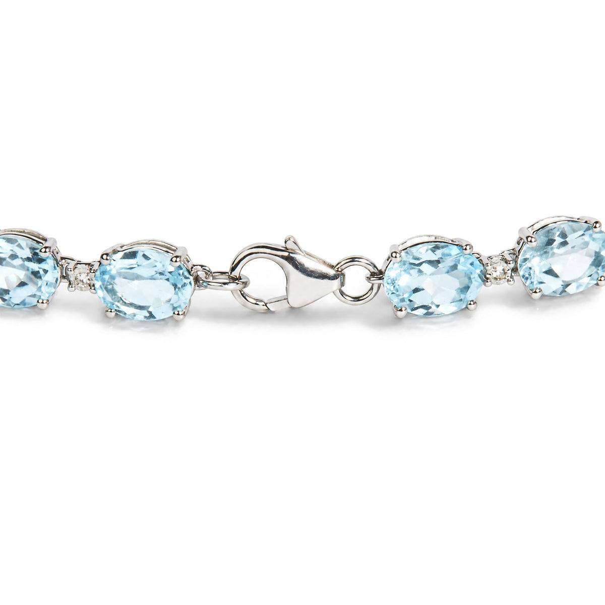 Close-up angled view of a white metal bracelet with oval blue gemstones and small round white gemstones in prong settings, showing the clasp.