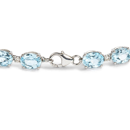 Close-up angled view of a white metal bracelet with oval blue gemstones and small round white gemstones in prong settings, showing the clasp.