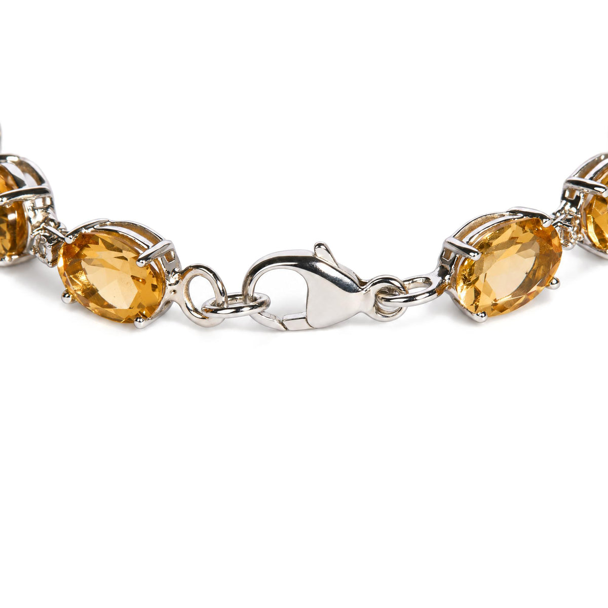 Close-up, angled shot of a white metal bracelet with oval yellow gemstones and small round white gemstones in prong settings, showing the lobster clasp.