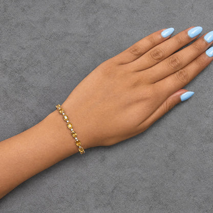 Close-up side angle of a model's hand wearing a white metal bracelet with alternating oval yellow gemstones and round white gemstones in prong settings.