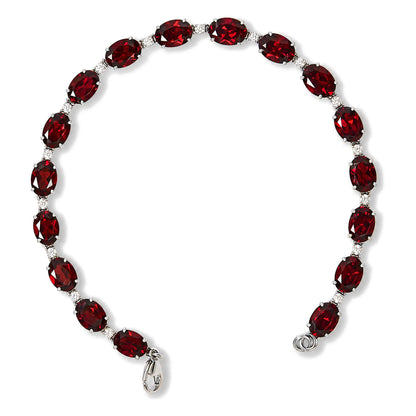 White metal bracelet with alternating oval red gemstones and round white gemstones in prong settings, shown flat on a white background from a top angle.