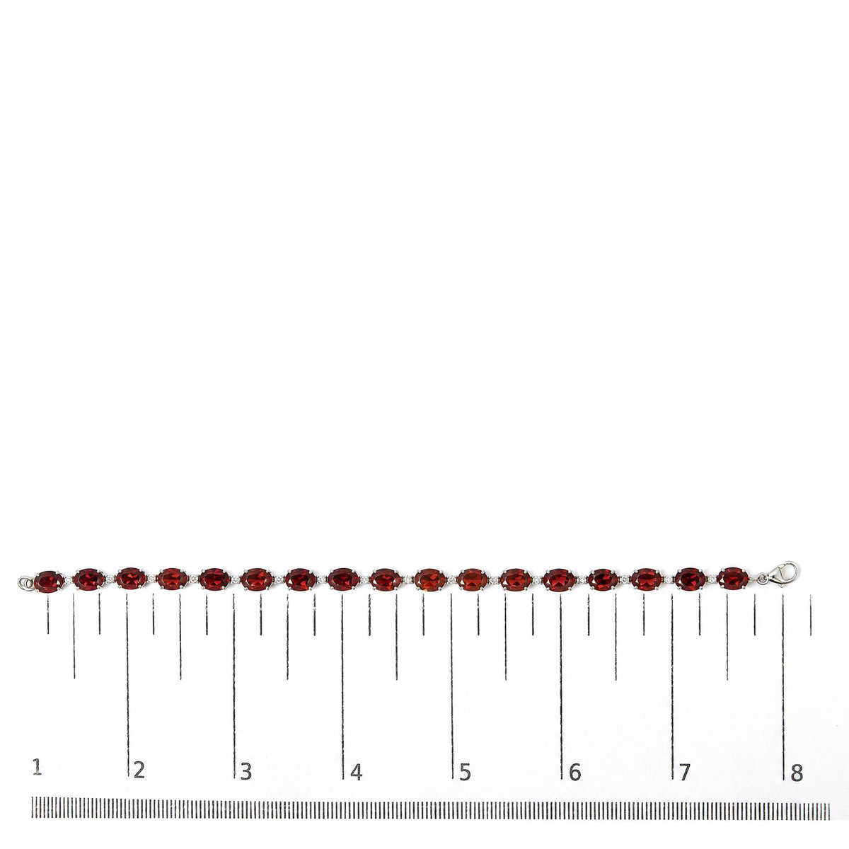 White metal bracelet with alternating oval-shaped red gemstones and small round white gemstones in prong settings, shown on a ruler scale from a top-down angle.