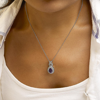 Close-up front view of a model wearing a white metal necklace with a pear-shaped purple gemstone pendant surrounded by round white gemstones in a pave setting.