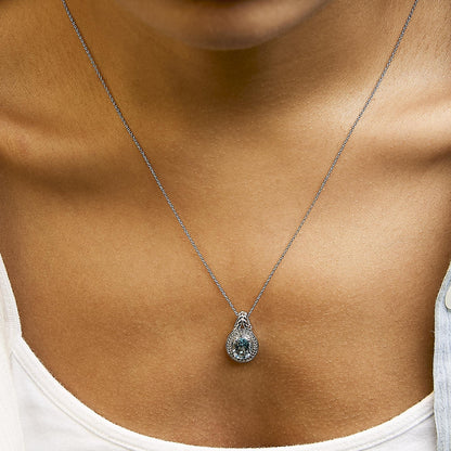 Close-up front view of necklace with a white metal chain and a pendant featuring an oval blue gemstone surrounded by round white gemstones in prong settings, shown worn on a model.