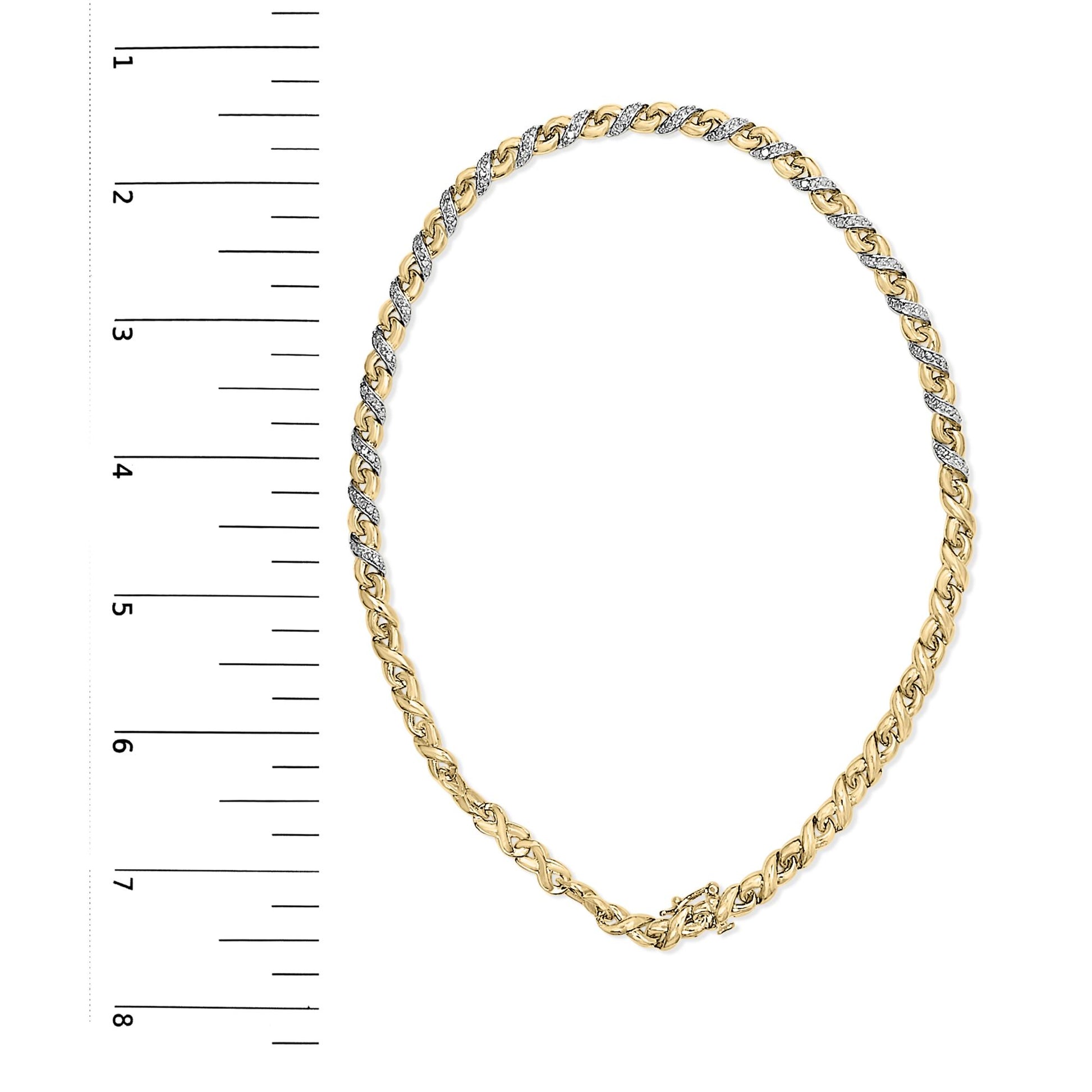 Top-down view of yellow metal necklace with alternating sections of white gemstones in prong settings, displayed on a ruler for size reference.