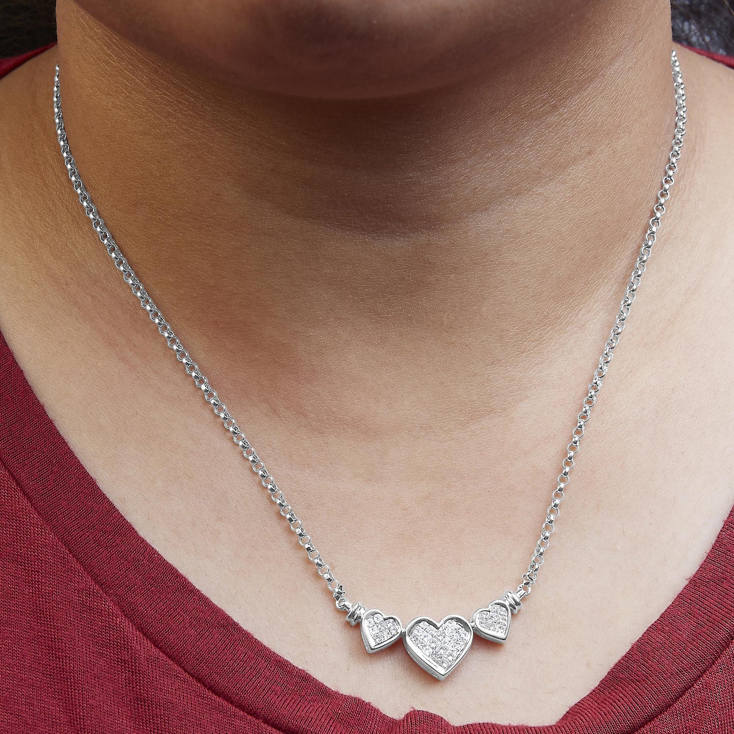 White metal necklace with three heart-shaped pendants featuring white gemstones, worn on a model, front-facing angle.