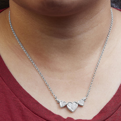 White metal necklace with three heart-shaped pendants featuring white gemstones, worn on a model, front-facing angle.
