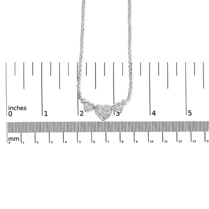 White metal necklace with three heart-shaped pendants set with white gemstones, shown hanging above a ruler for size reference, front view.