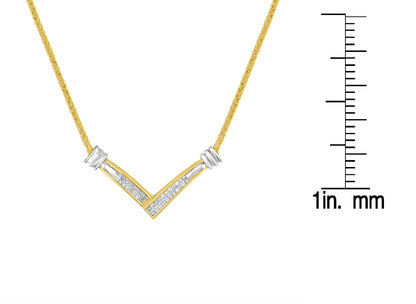 Close-up front view of a yellow and white metal necklace with a V-shaped pendant featuring white gemstones in a channel setting, displayed next to a ruler for size reference.