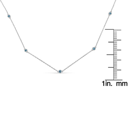 Front-facing shot of a white metal necklace with five round blue gemstones in bezel settings, displayed next to a ruler for size reference.
