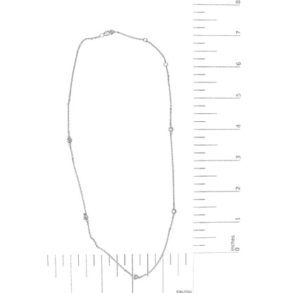 Top-down view of a white metal necklace with five round white gemstones in bezel settings, displayed on a ruler for size reference.