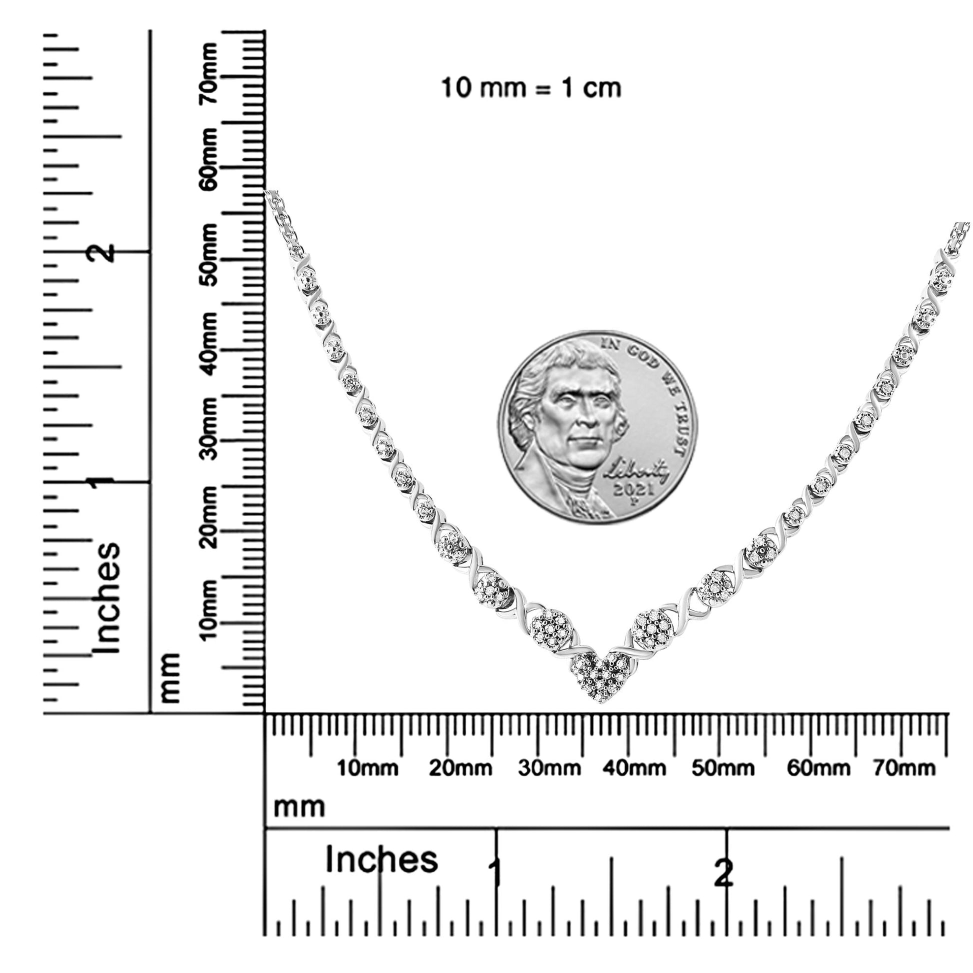 White metal necklace with round white gemstones in a pave setting arranged in a V shape, displayed flat on a ruler and scale for size reference, top-down angle.