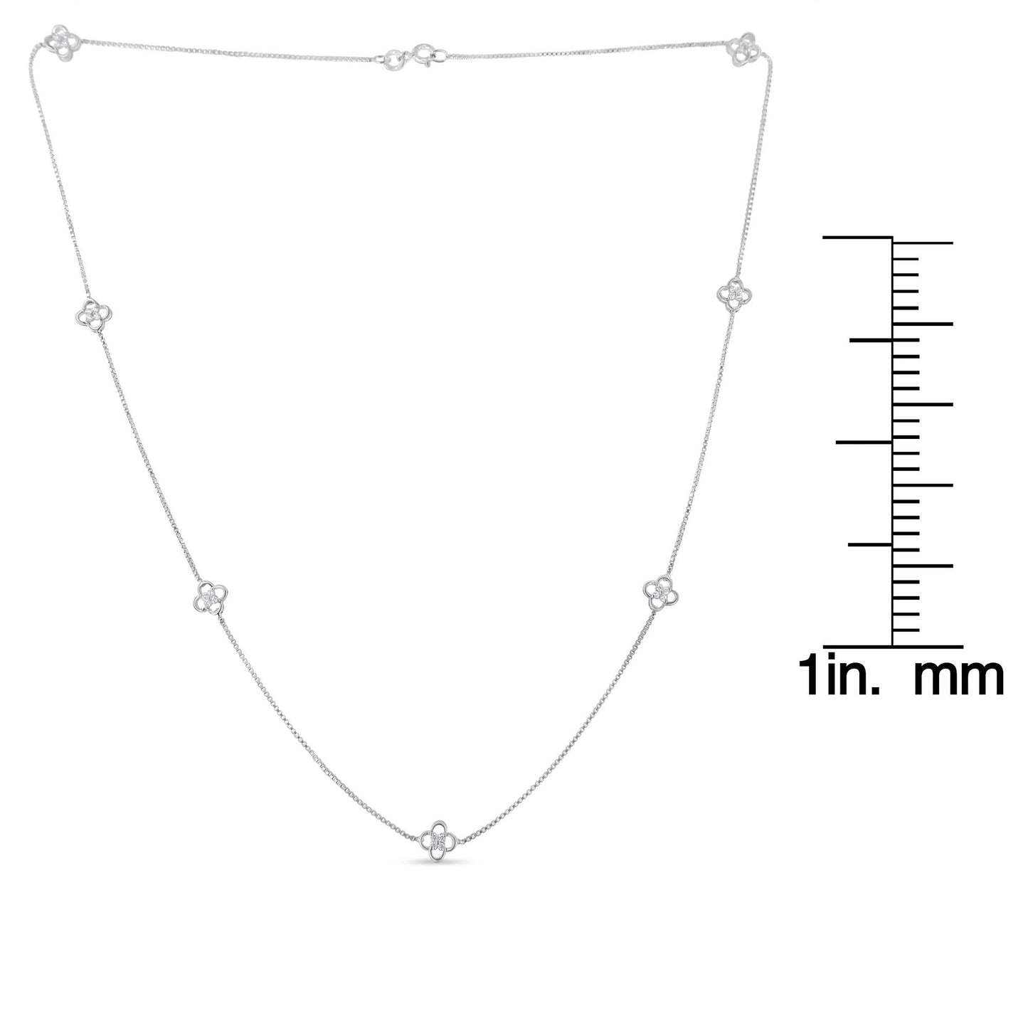 White metal necklace with round white gemstones in prong settings arranged in small floral motifs, laid flat with a ruler for size reference, top-down angle.